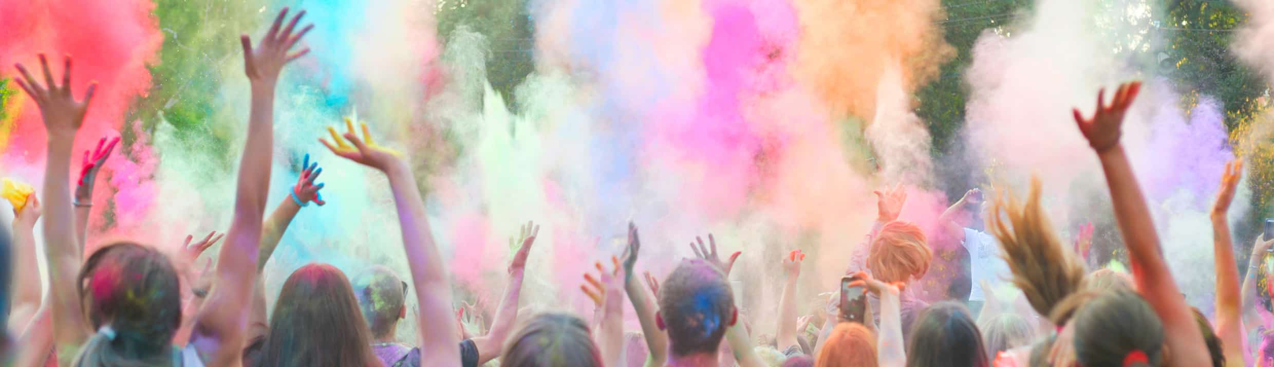 Festivalgangers gooien kleurrijke poeder tijdens een festival de lucht in.