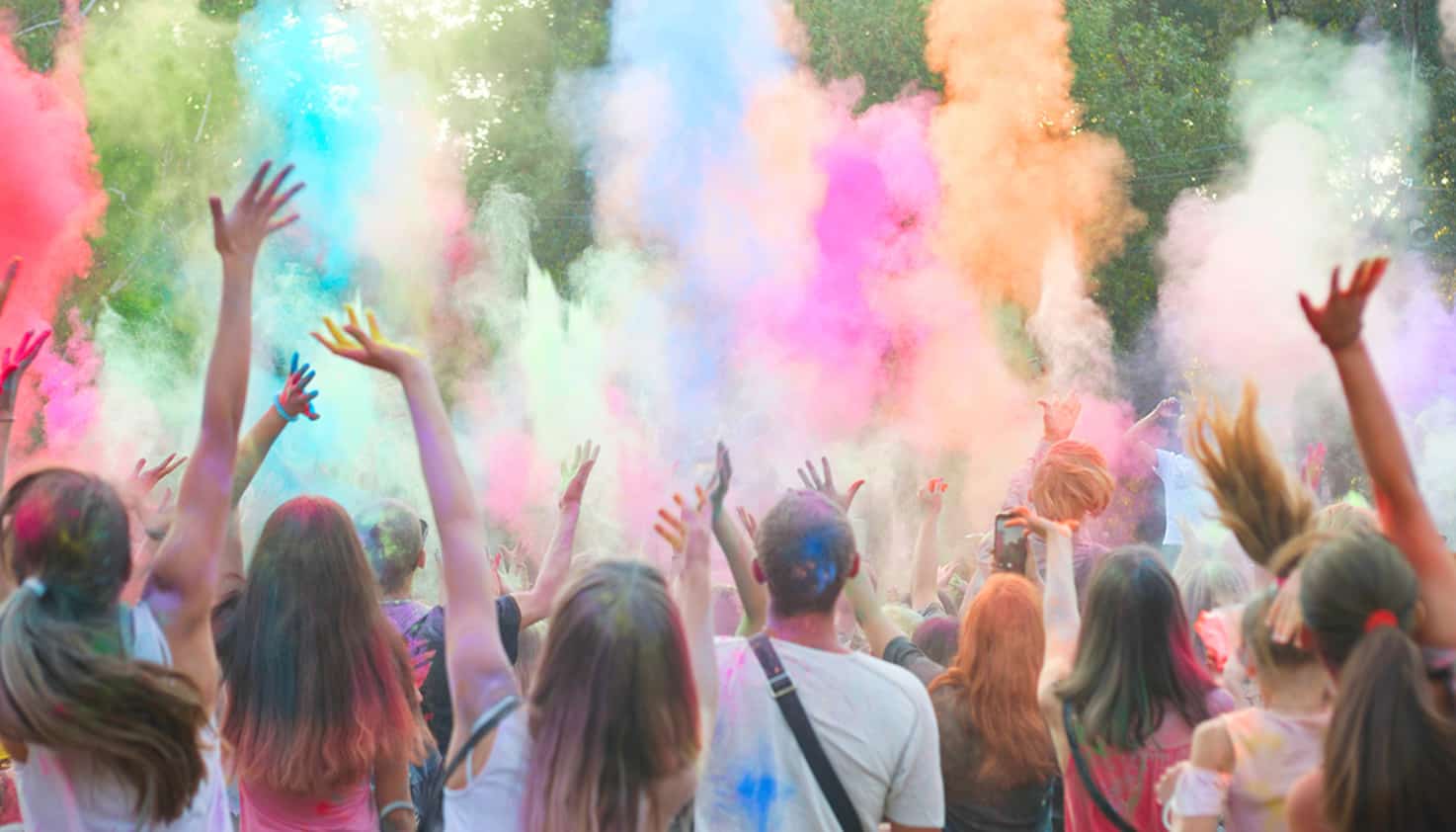 Festivalgangers gooien kleurrijke poeder tijdens een festival de lucht in.