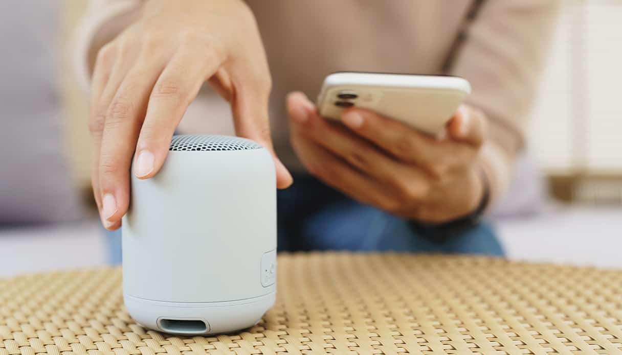 Bluetooth speaker staat op de salontafel en wordt gekoppeld met de telefoon.