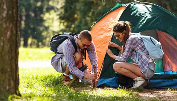 Koppel is de tent aan het opzetten, ze zijn aan het kamperen in het bos.