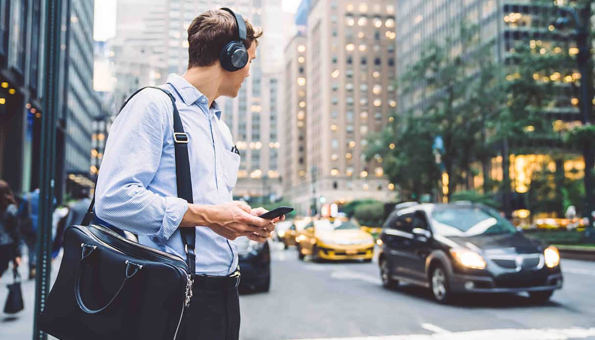 Man zit aan zijn bureau te kijken naar zijn laptop terwijl hij ook een koptelefoon met noise cancelling op heeft.