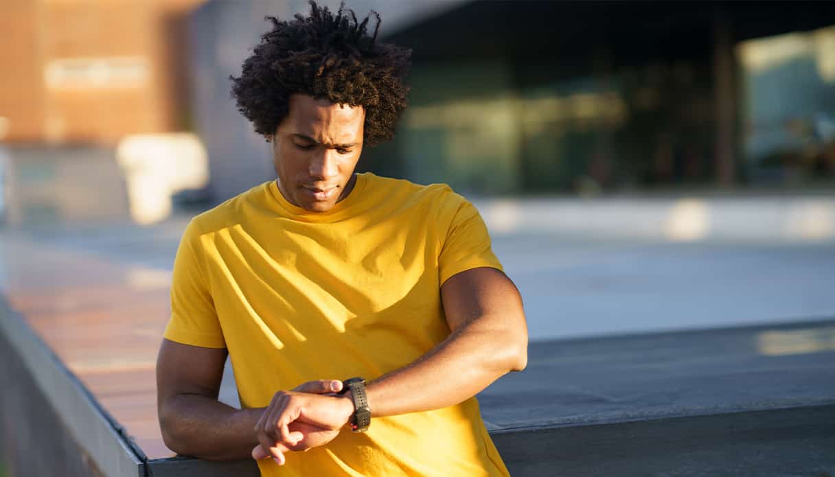 Man is aan het sporten en kijkt tijdens zijn work out op zijn smartwatch om zijn resultaten te bekijken.