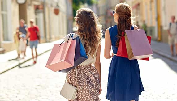 Twee vrouwen lopen door de winkelstraat met allebei meerdere tassen in de hand.