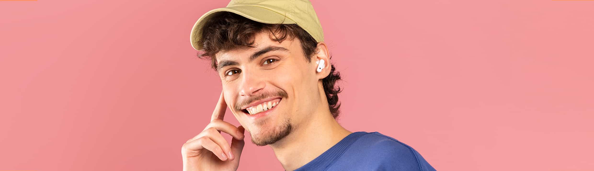 Man heeft draadloze Apple AirPods in en lacht vriendelijk naar de camera.