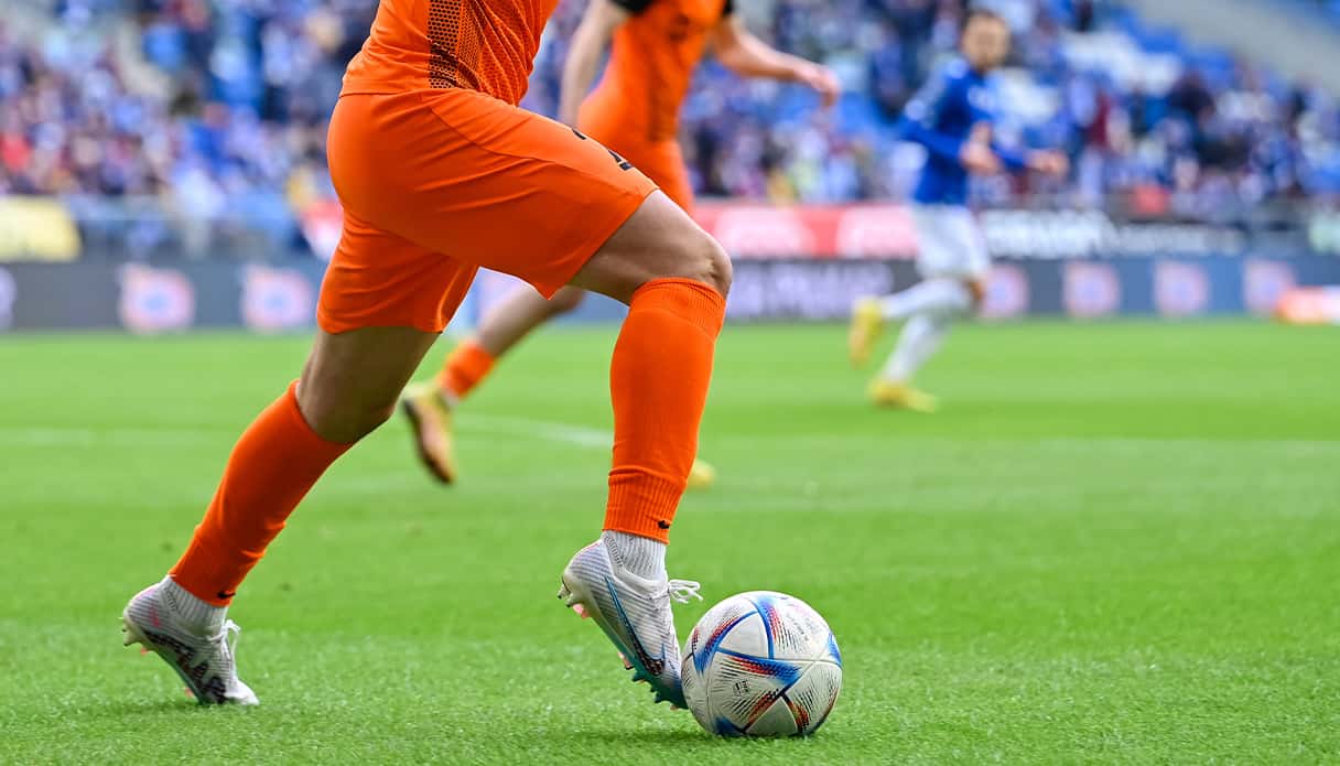 Voetballer van Nederlands elftal heeft de bal aan zijn voeten en staat op het punt een doelpunt te scoren.