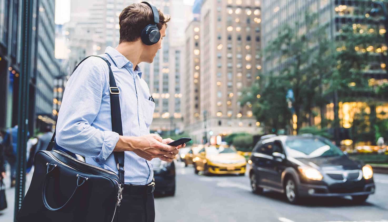 Man zit aan zijn bureau te kijken naar zijn laptop terwijl hij ook een koptelefoon met noise cancelling op heeft.