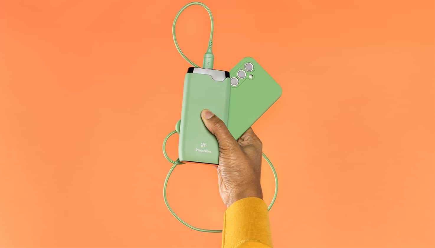 Knaloranje achtergrond met een opvallende groene kleur powerbank en matchende telefoon.