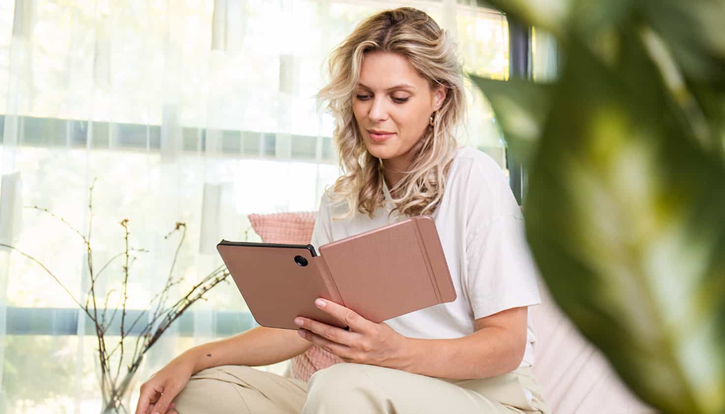 Een vrouw leest op een e-reader met roze hoes van Tolino.