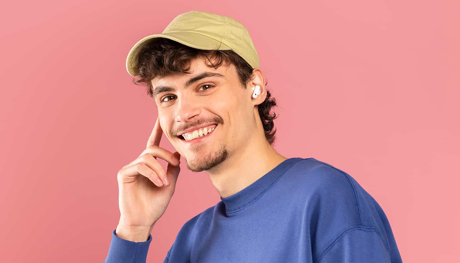 Man heeft draadloze Apple AirPods in en lacht vriendelijk naar de camera.