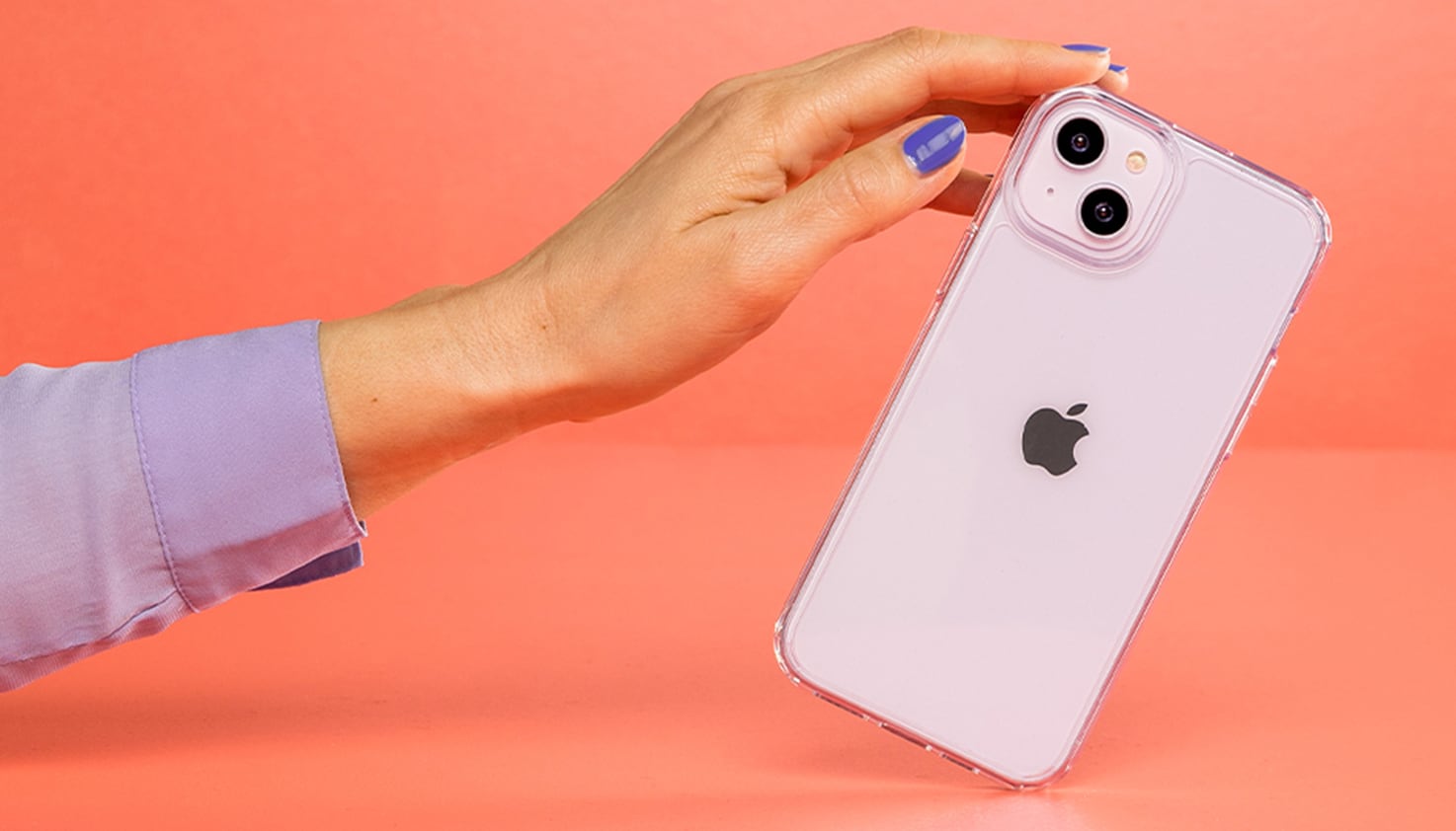 Een vrouwenhand die een iPhone vasthoudt, de achtergrond is oranje.