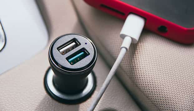 Telefoon ligt aan de car charger op te laden, Lightning kabel zit in de smartphone.