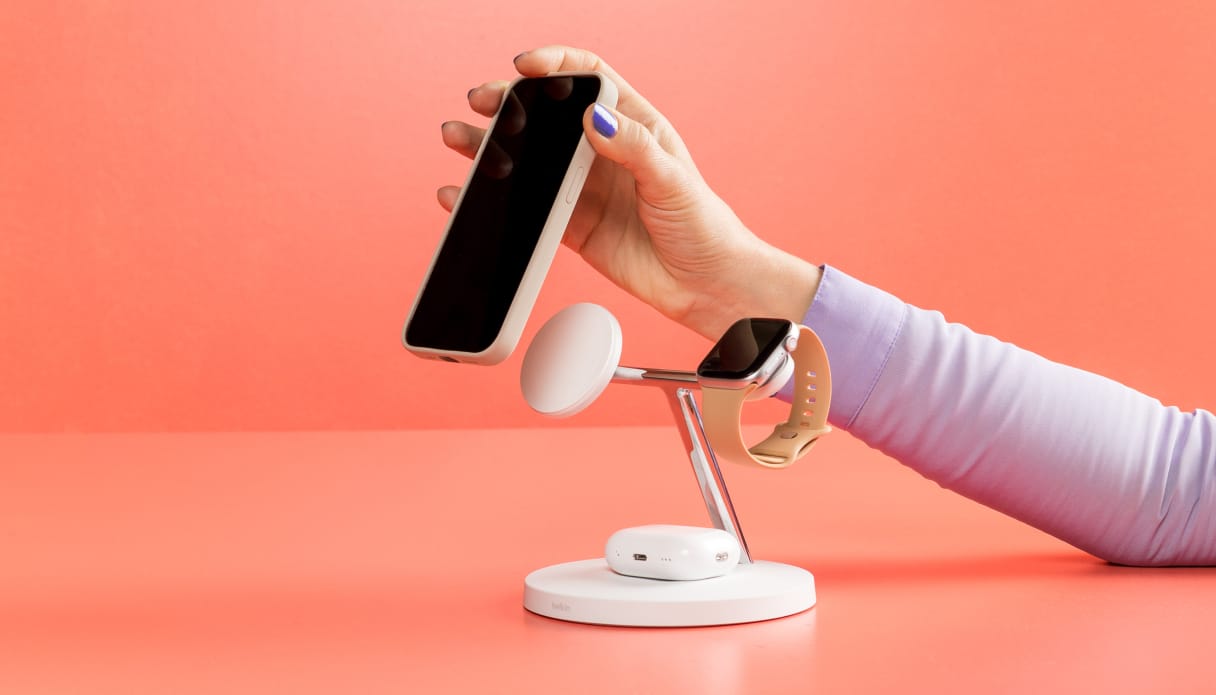 Een draadloze oplaad standaard met een telefoon, smartwatch en oordopjes.