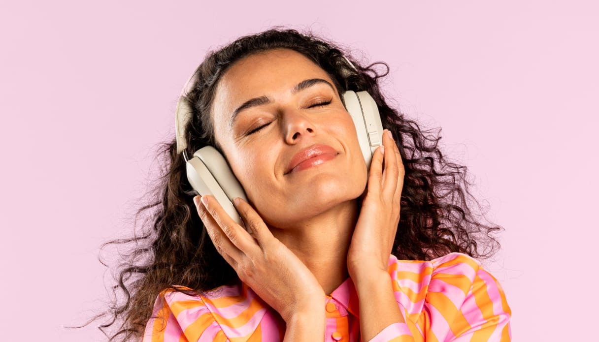 Een vrouw met een beige koptelefoon met noise cancelling.