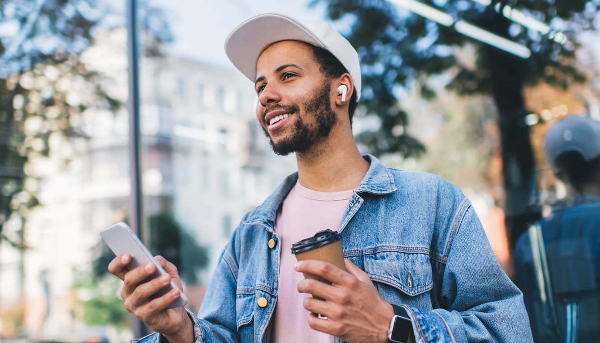 Je ziet een man met zijn AirPods in en iPhone in zijn hand