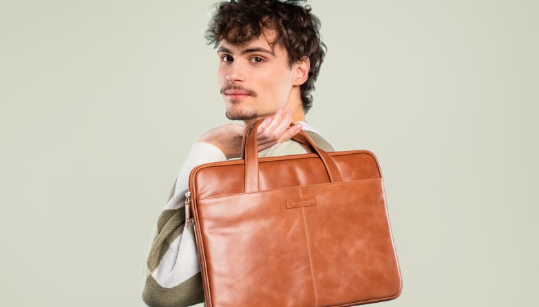 Een man heeft een cognac lederen laptoptas in zijn handen