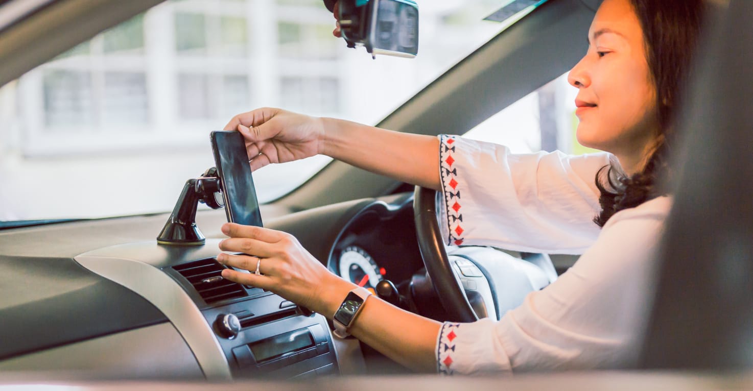 Vrouw plaatst haar telefoon in een telefoonhouder in de auto