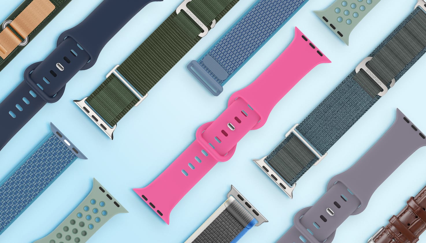 Een collectie van verschillende materialen en kleuren smartwatchbandjes liggen uitgespreid op een lichtblauwe achtergrond. 