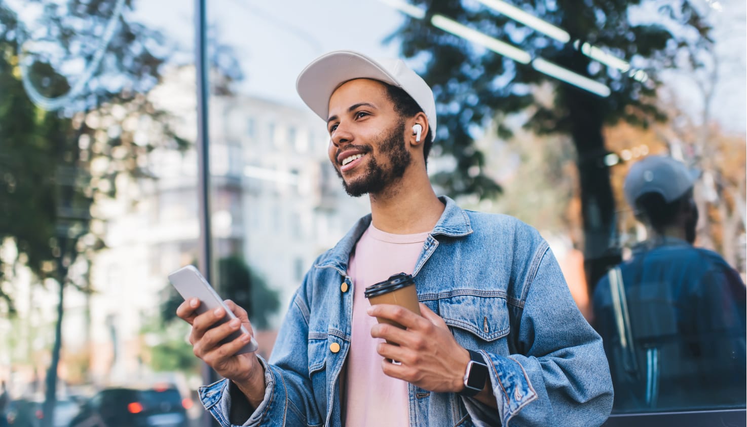 Je ziet een man met zijn AirPods in en iPhone in zijn hand